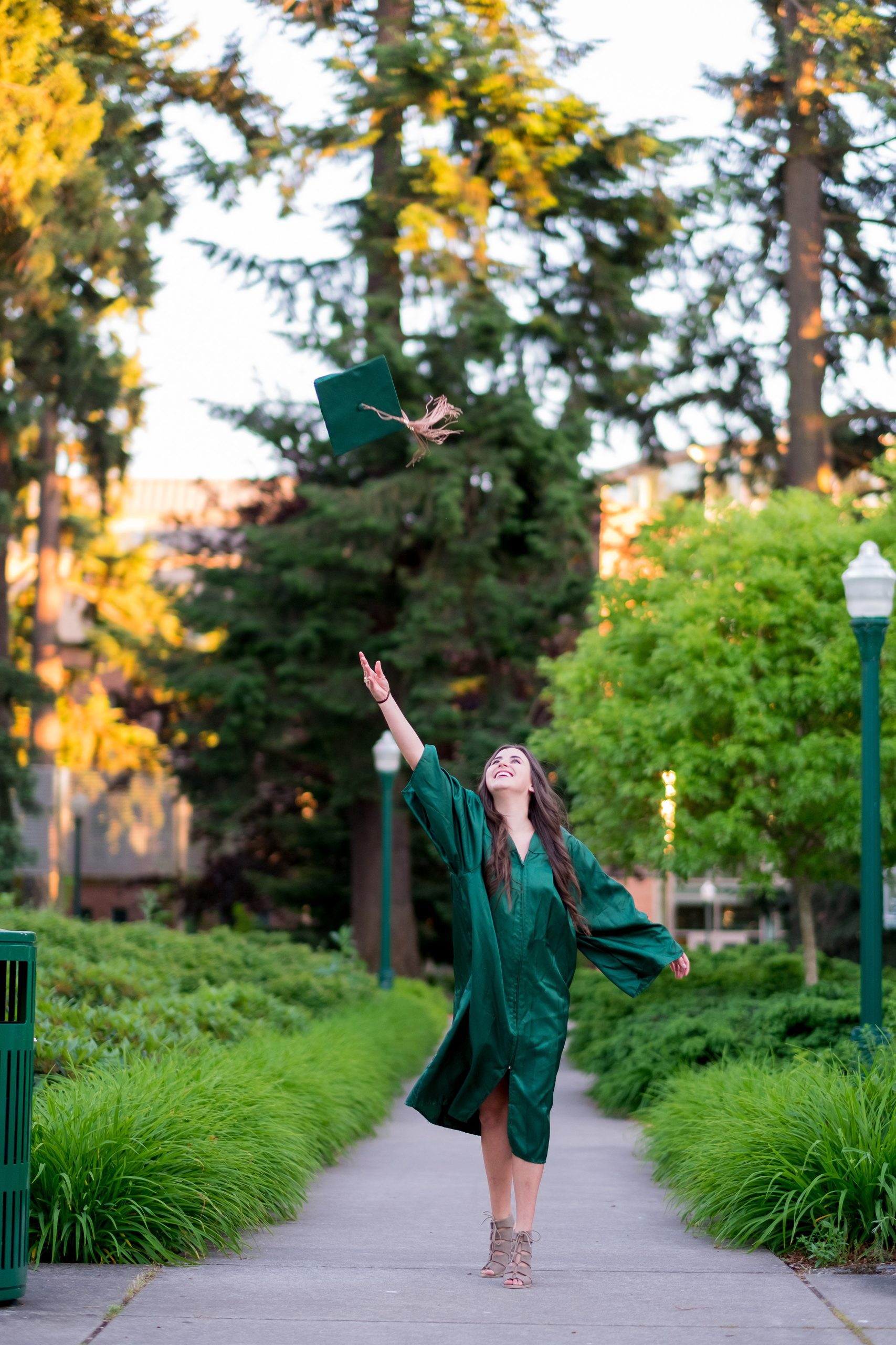 College Grad on Campus in Oregon College grad student throwing hat in the air before graduation ceremonies.